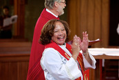 Pastor Beverly clapping hands at her installation service. Bishop Gordy is behind her